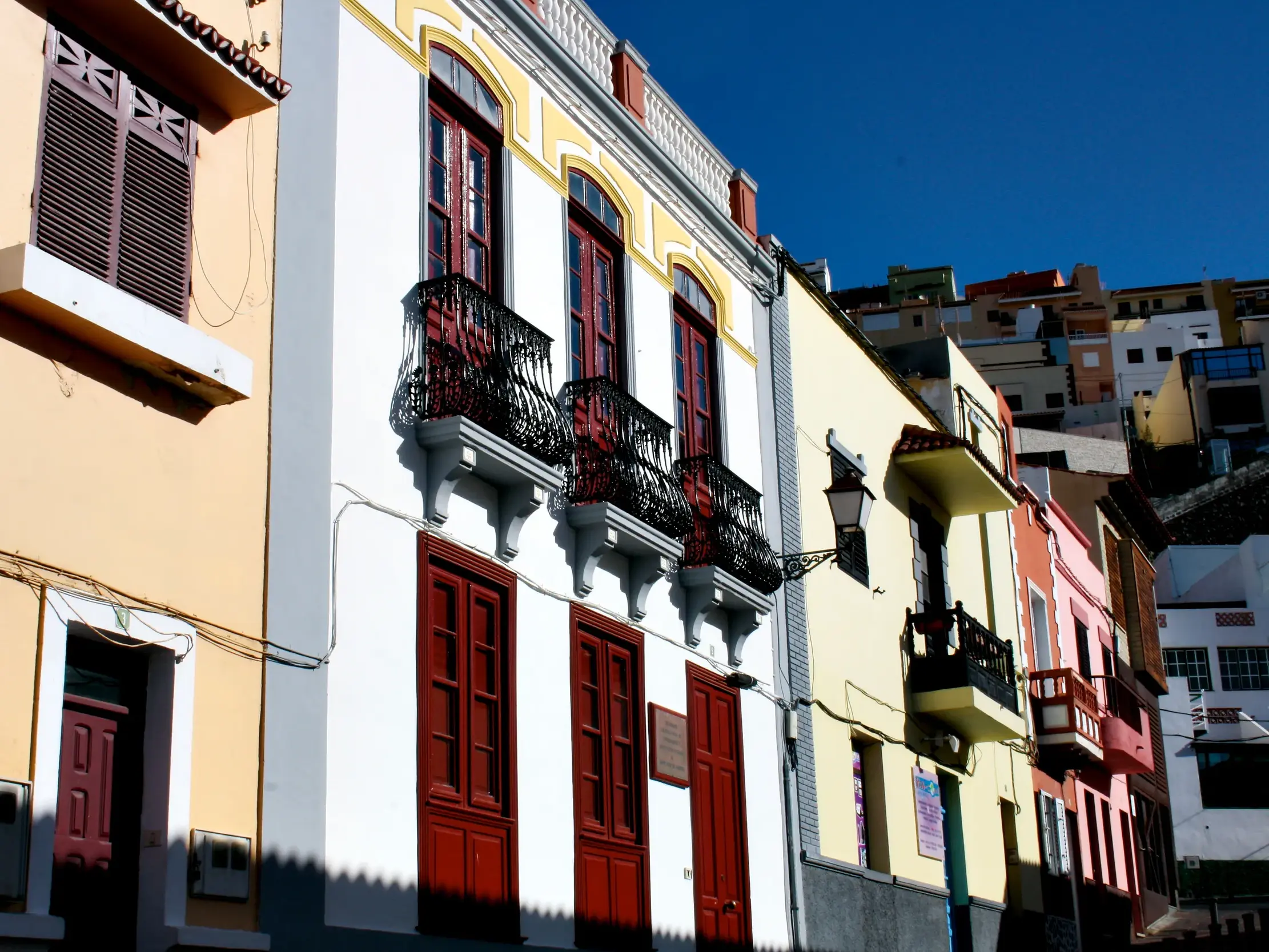 Bunte Häuserfassaden mit traditionellen Balkonen in einer sonnigen Gasse in San Sebastián auf der Insel La Gomera.