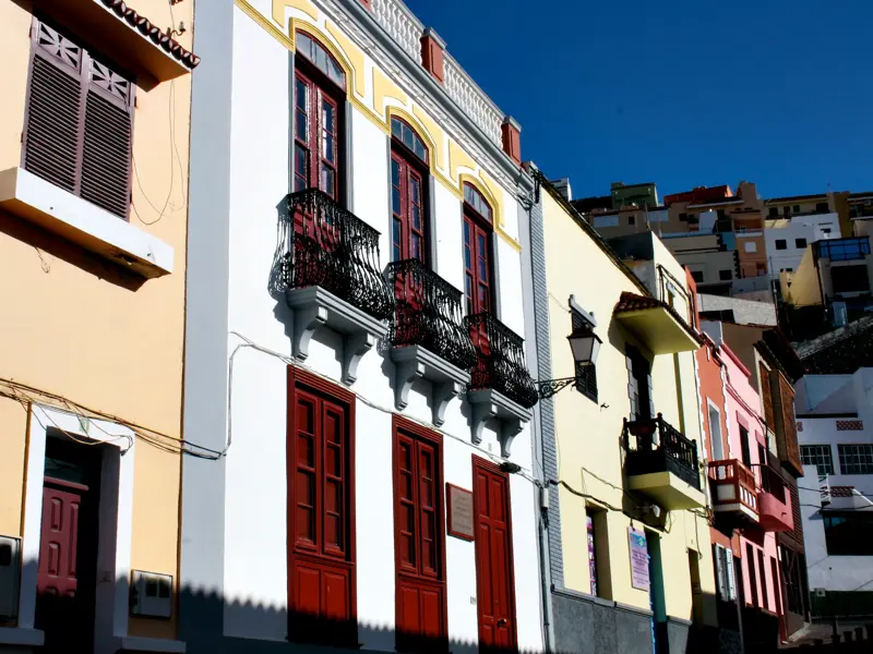 Bunte Häuserfassaden mit traditionellen Balkonen in einer sonnigen Gasse in San Sebastián auf der Insel La Gomera.