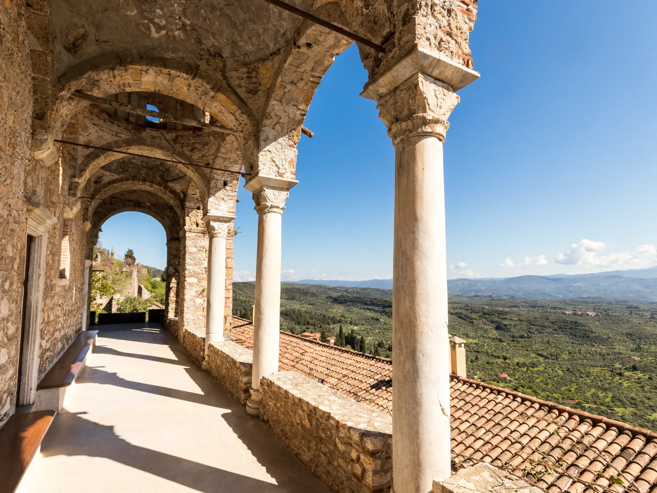 Ein steinerner Arkadengang im Kloster Pantanassa in Mistra bietet einen weiten Blick über die grünen Hügel des Peloponnes.