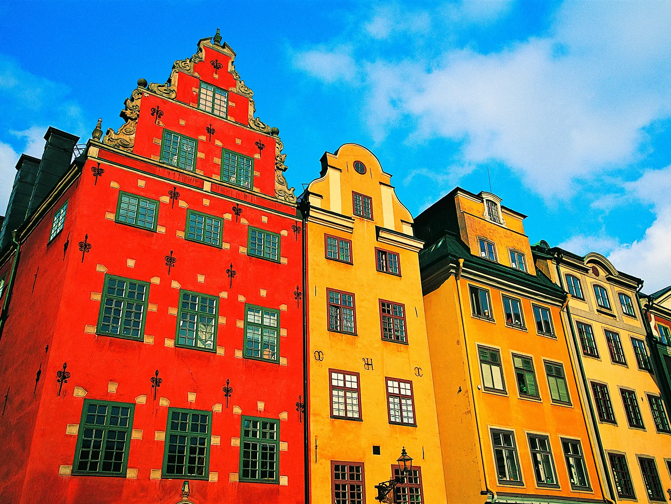 Farbenfrohe Giebelhäuser am Platz Stortorget in Stockholms historischer Altstadt Gamla Stan unter blauem Himmel.