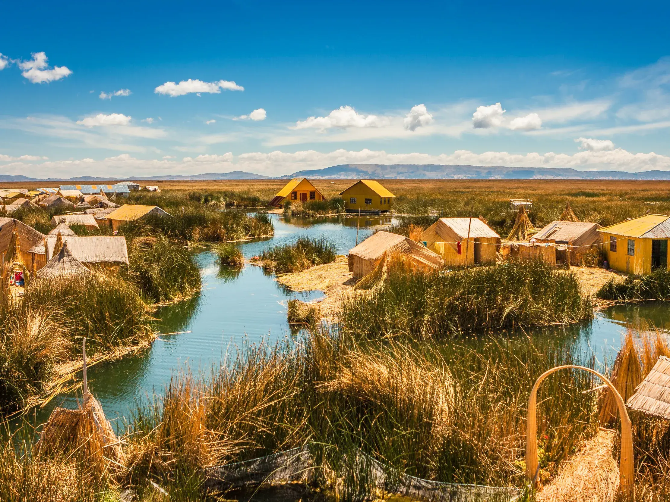 Sonnige Ansicht der schwimmenden Inseln der Uros am Titicacasee mit traditionellen Hütten aus Totora-Schilfrohren.