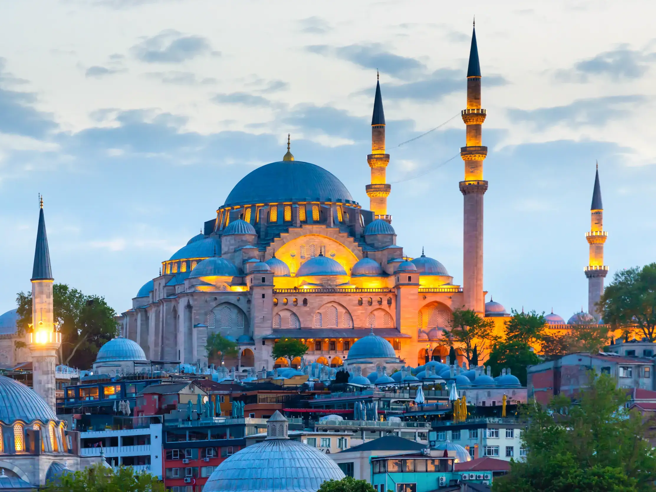 Die prachtvolle Süleyman-Moschee in Istanbul, deren Kuppeln und Minarette in der Abenddämmerung hell erleuchtet sind.