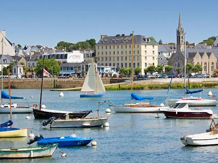 Boote im Segelhafen von Bénodet an der bretonischen Riviera, im Hintergrund das Hotel Abbatiale und der Kirchturm der Stadt.
