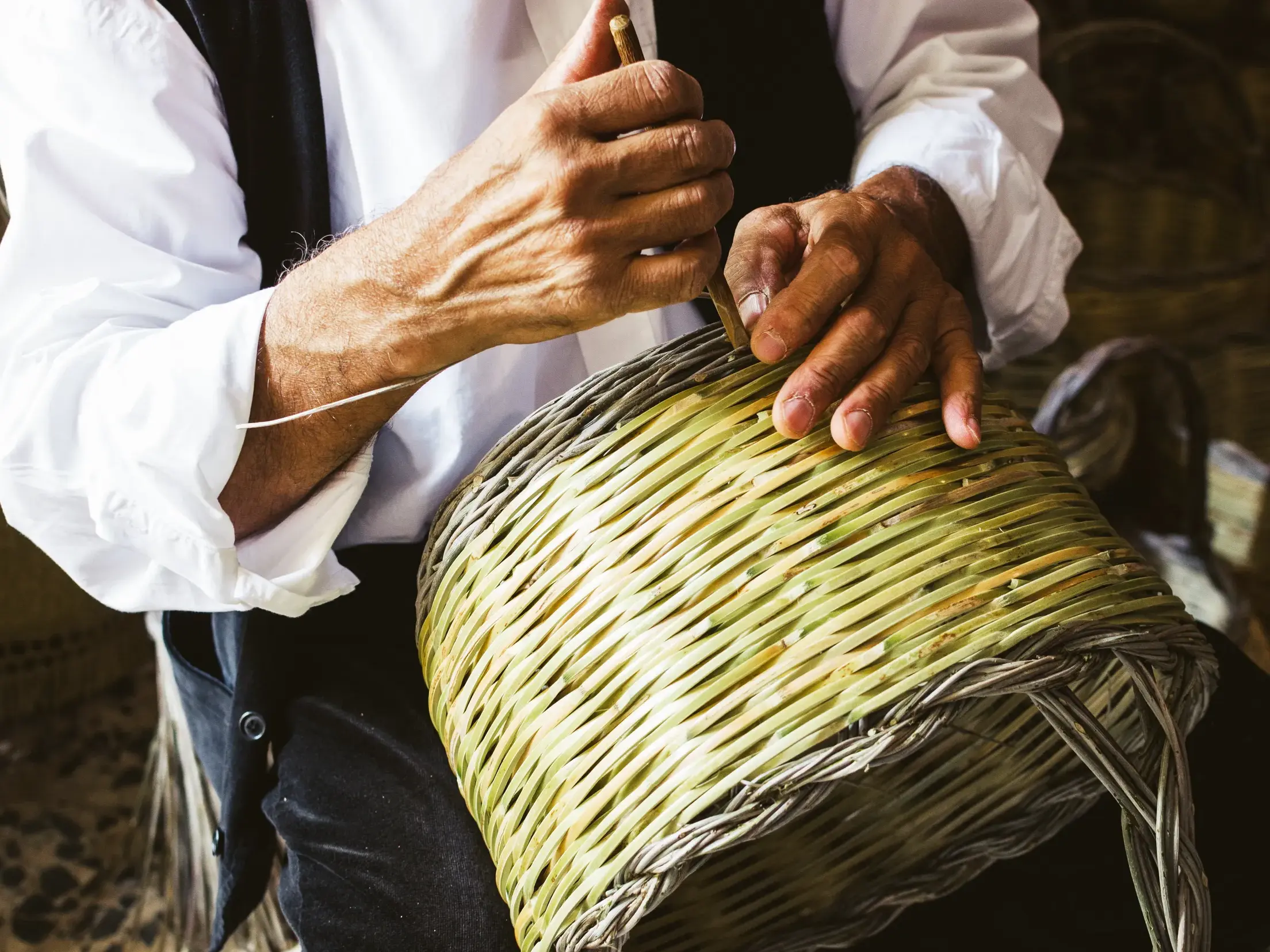 Nahaufnahme der geübten Hände eines Korbflechters, der in Castelsardo auf Sardinien traditionelles Handwerk demonstriert.