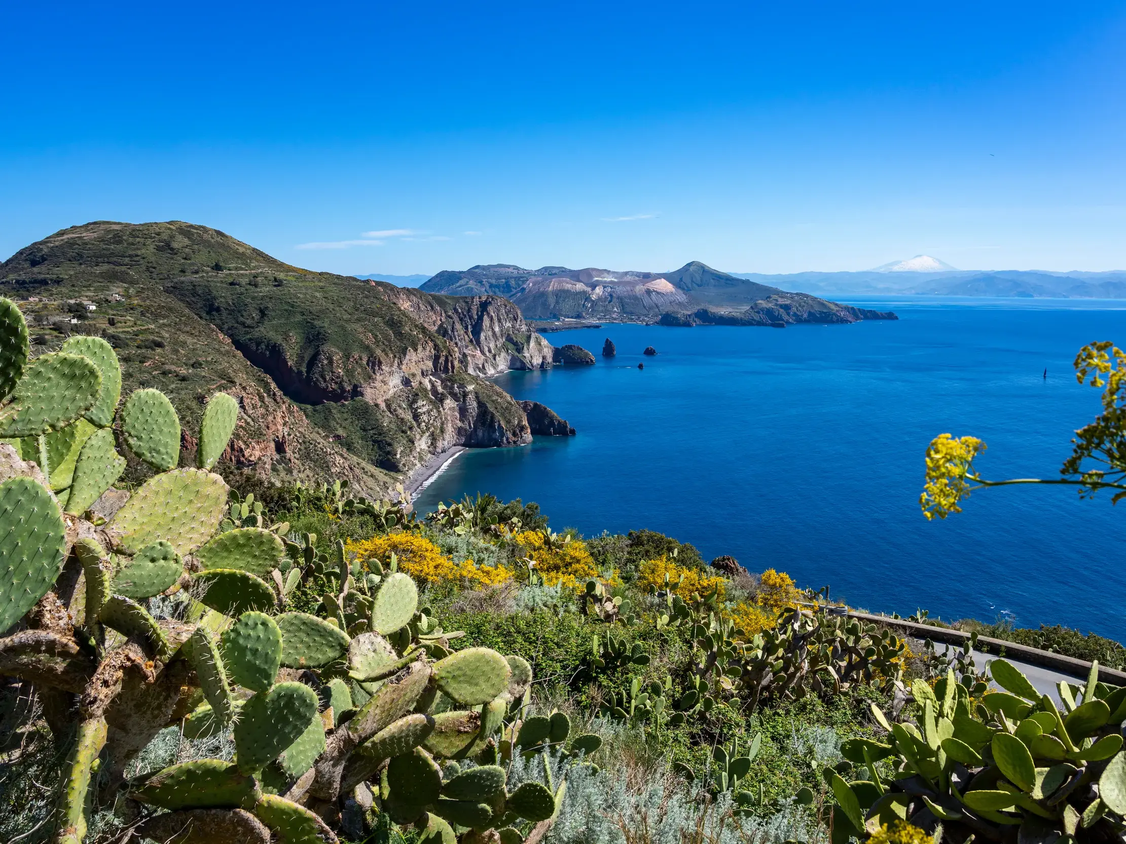 Aussicht bei einer Wanderung auf den Äolischen Inseln über die Steilküste und das Meer zur Insel Vulcano und dem Ätna.
