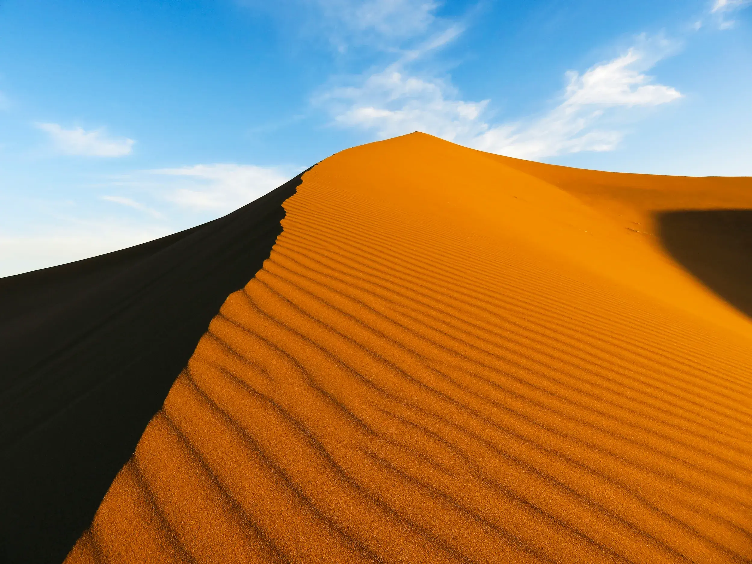 Majestätischer Dünenkamm in Marokkos Sahara mit feiner Sandstruktur, ein Highlight beim Wüstentrekking im Erg Chegaga.