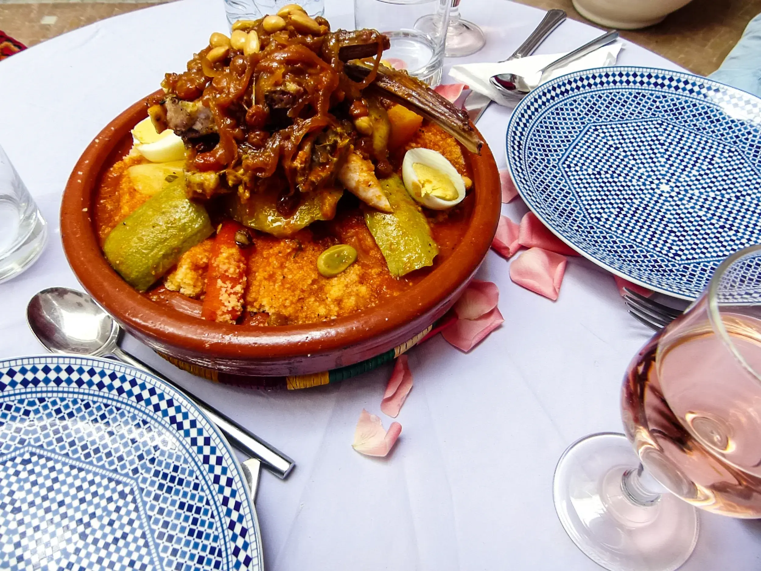 Festlich servierter marokkanischer Couscous mit Lamm und Gemüse in einer Tajine auf einem dekorierten Tisch in Marrakesch.