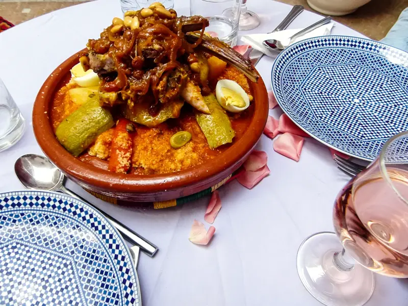 Festlich servierter marokkanischer Couscous mit Lamm und Gemüse in einer Tajine auf einem dekorierten Tisch in Marrakesch.