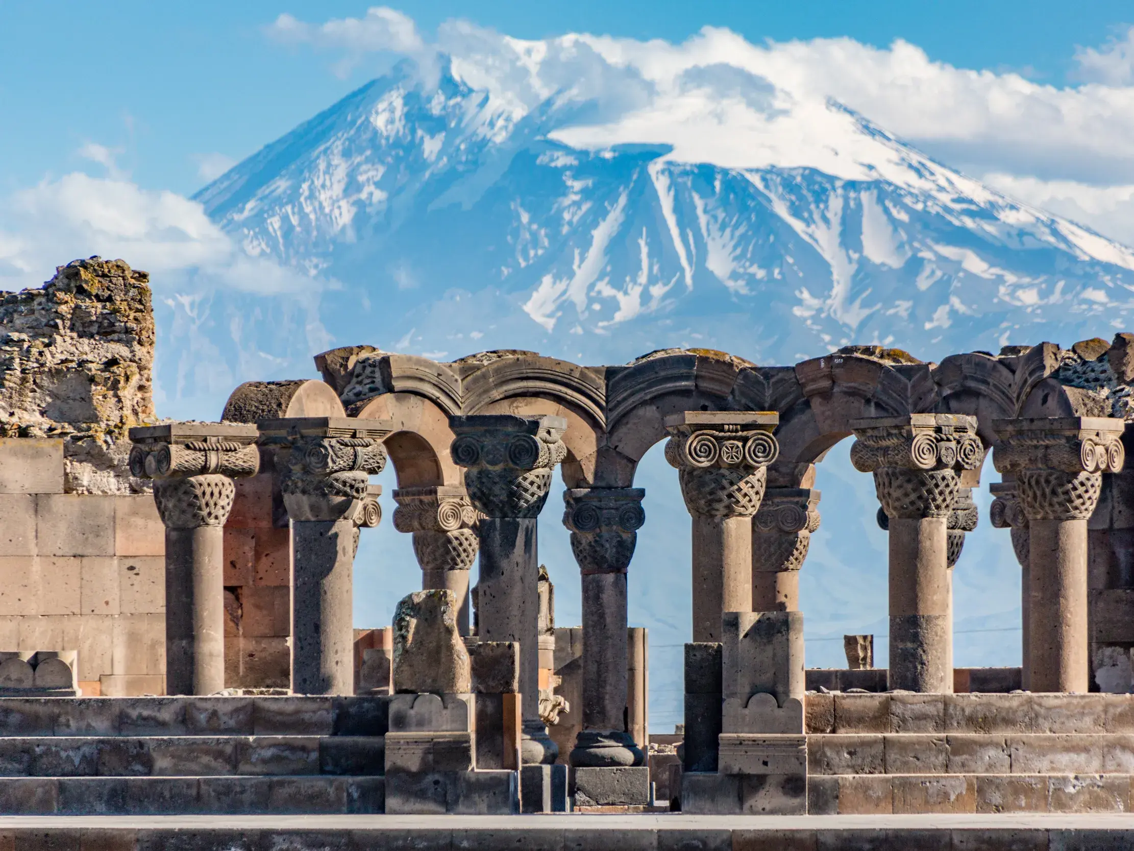 Steinerne Säulen der Ruinen der Swartnoz-Kathedrale (UNESCO) vor dem majestätischen, schneebedeckten Berg Ararat in Armenien.