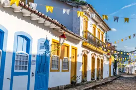 Sonnige Kopfsteinpflastergasse in Paraty mit weißen Kolonialhäusern, bunten Türen und festlichen Wimpelketten.