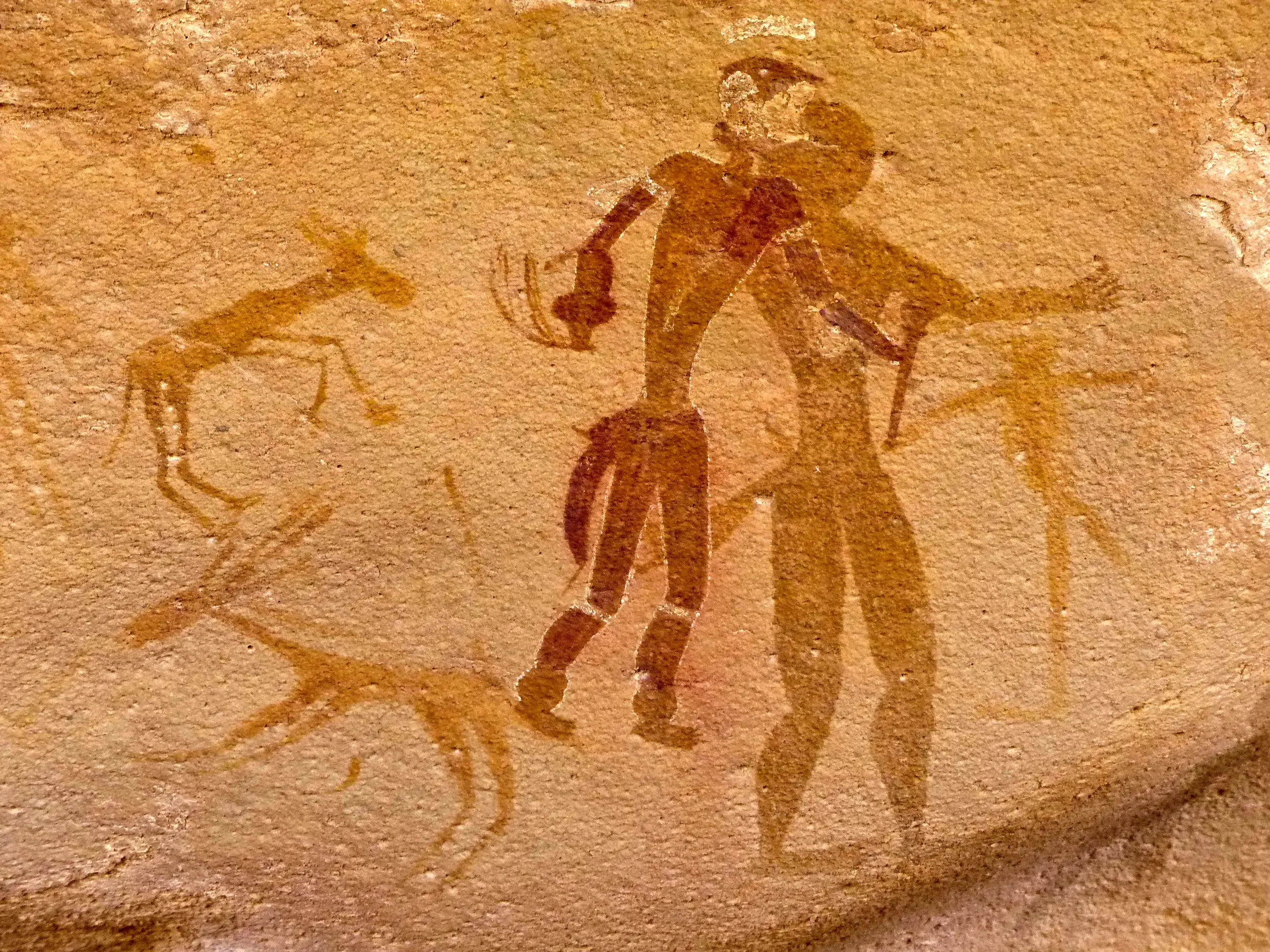 Kunstvolle prähistorische Felsmalerei von Menschen und Tieren auf einer Trekkingreise durch das Tassili n'Ajjer.