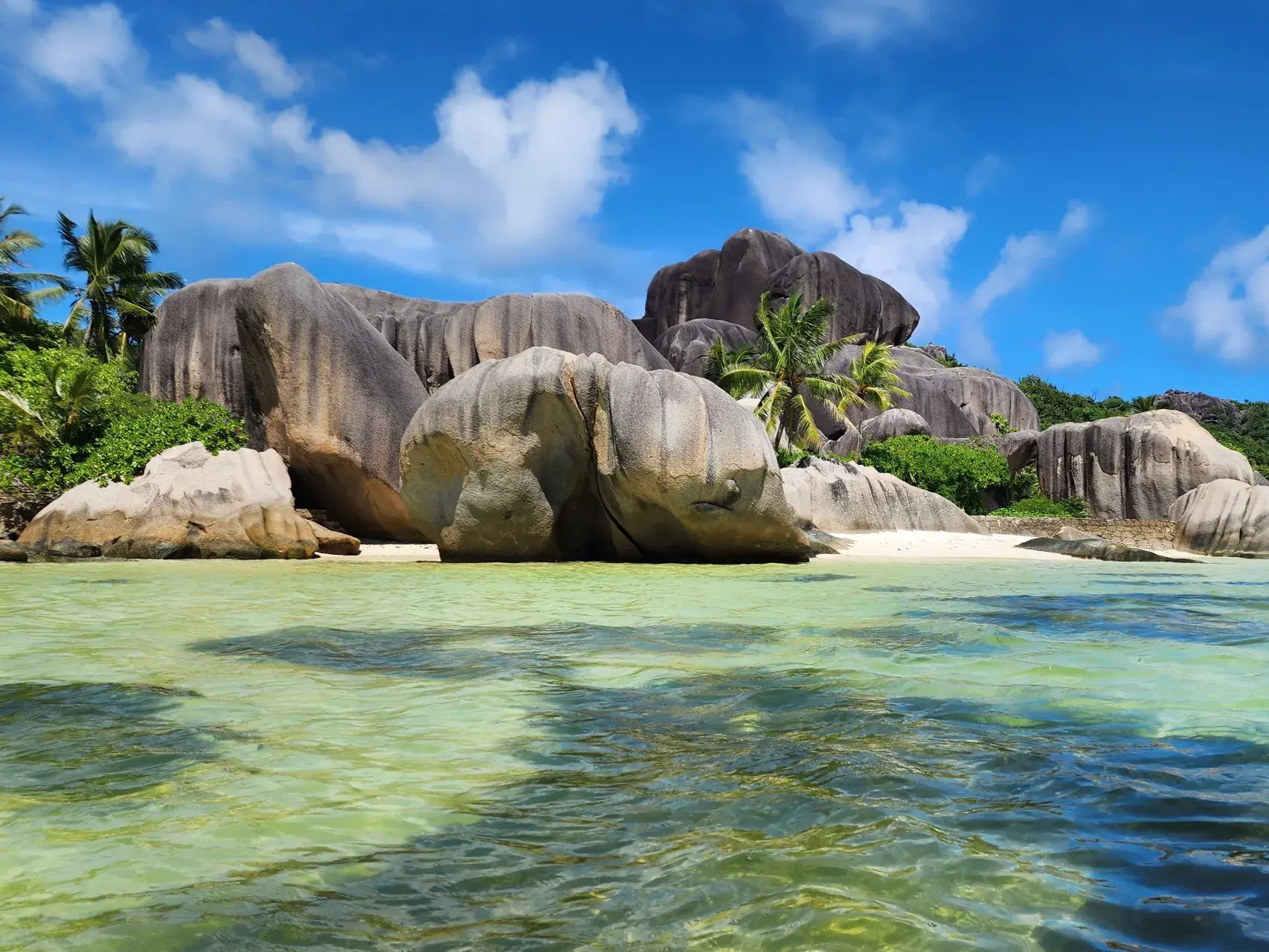 Blick vom Wasser auf die markanten Granitfelsen und Palmen am Traumstrand Anse Source d'Argent auf La Digue, Seychellen.