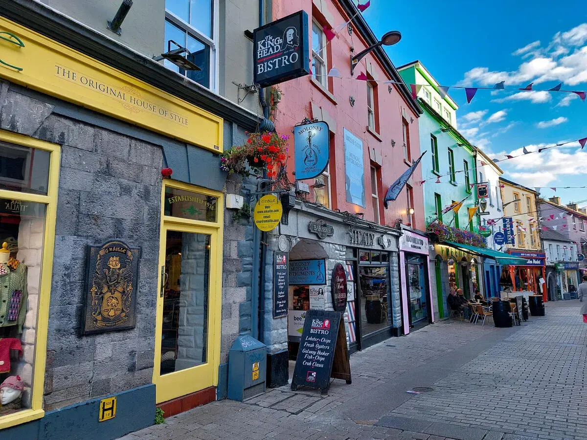 Farbenfrohe Kopfsteinpflastergasse in Galway mit bunten Fassaden traditioneller Pubs bei einem Stadtbummel an Irlands Westküste.