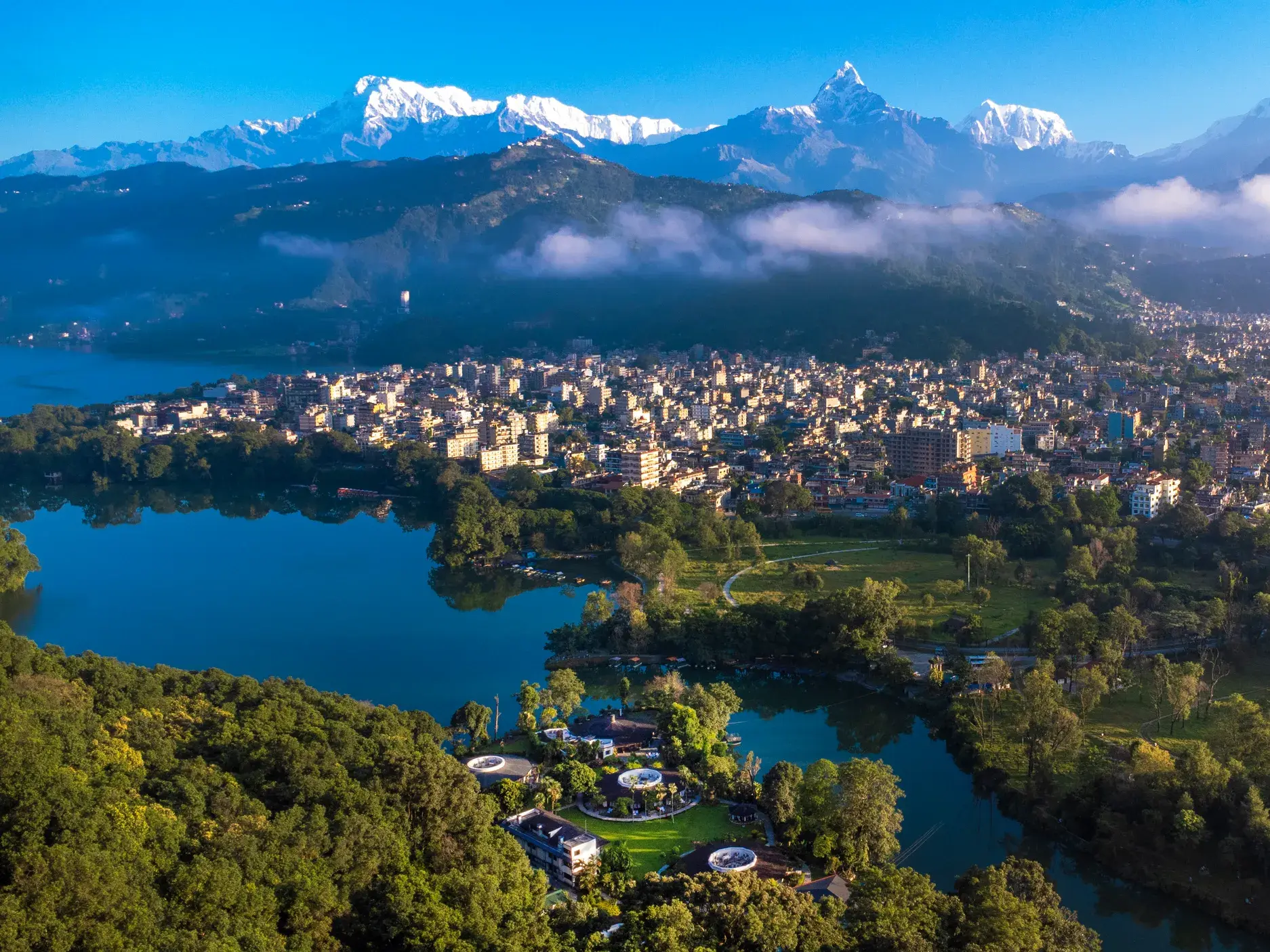 Panoramablick auf die Stadt Pokhara am Phewa-See vor der majestätischen, schneebedeckten Kulisse des Annapurna-Massivs.