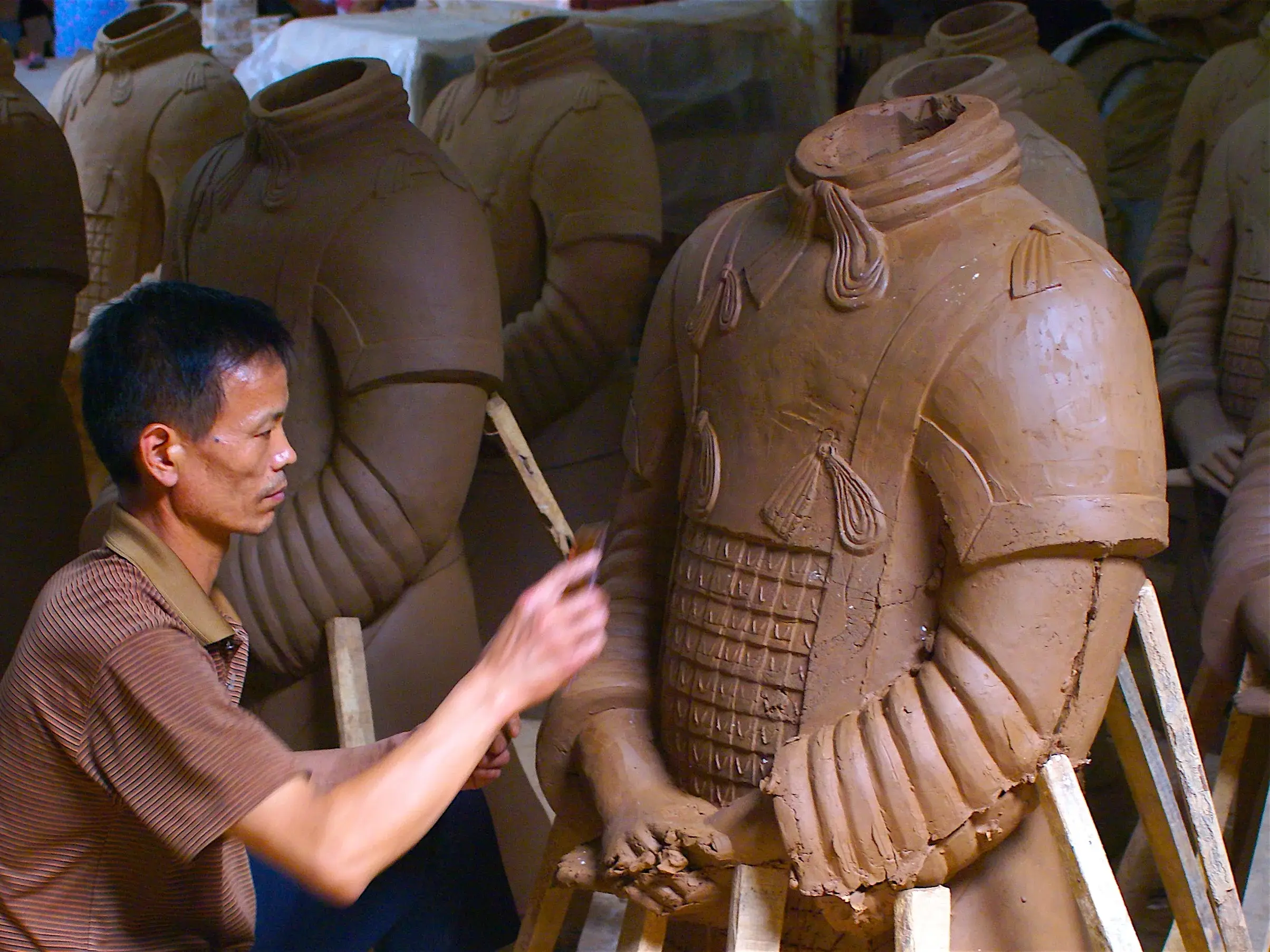 Ein chinesischer Handwerker modelliert in einer Werkstatt bei Xian filigrane Details an der Tonrüstung einer Terrakotta-Krieger-Replik.