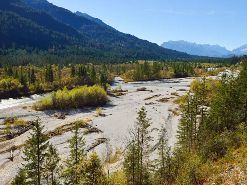 Blick beim Trekking auf die unberührte Wildflusslandschaft der Isar in Bayrisch-Kanada mit dem Karwendel im Hintergrund.