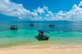 Ausflugsboote mit blauem Dach ankern in der türkisfarbenen Lagune der Mamanuca-Inseln auf Fiji unweit des Sandstrandes.