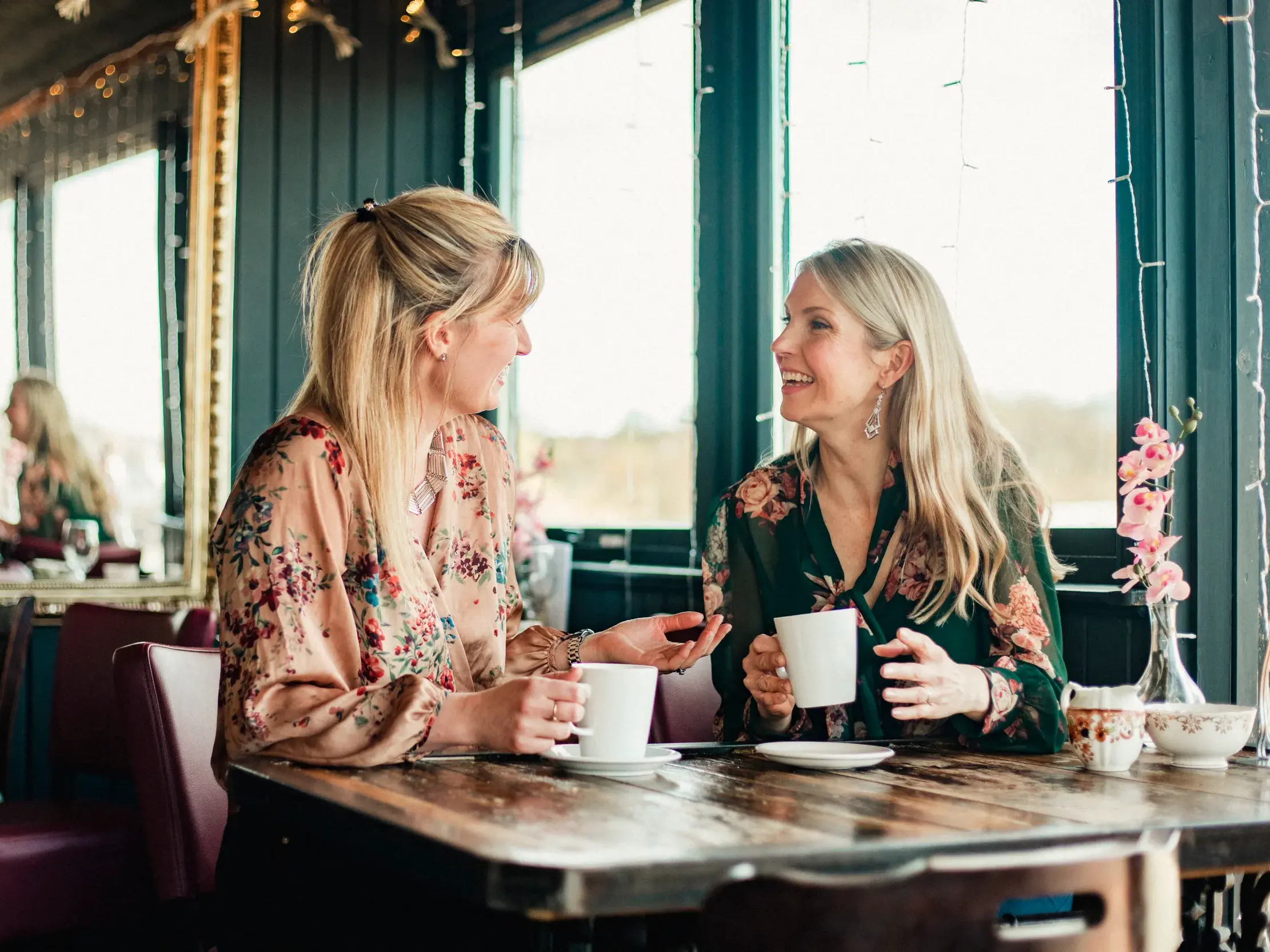 Zwei Frauen unterhalten sich entspannt bei einer Tasse Kaffee im Café an Bord des Kreuzfahrtschiffes MS Hamburg.