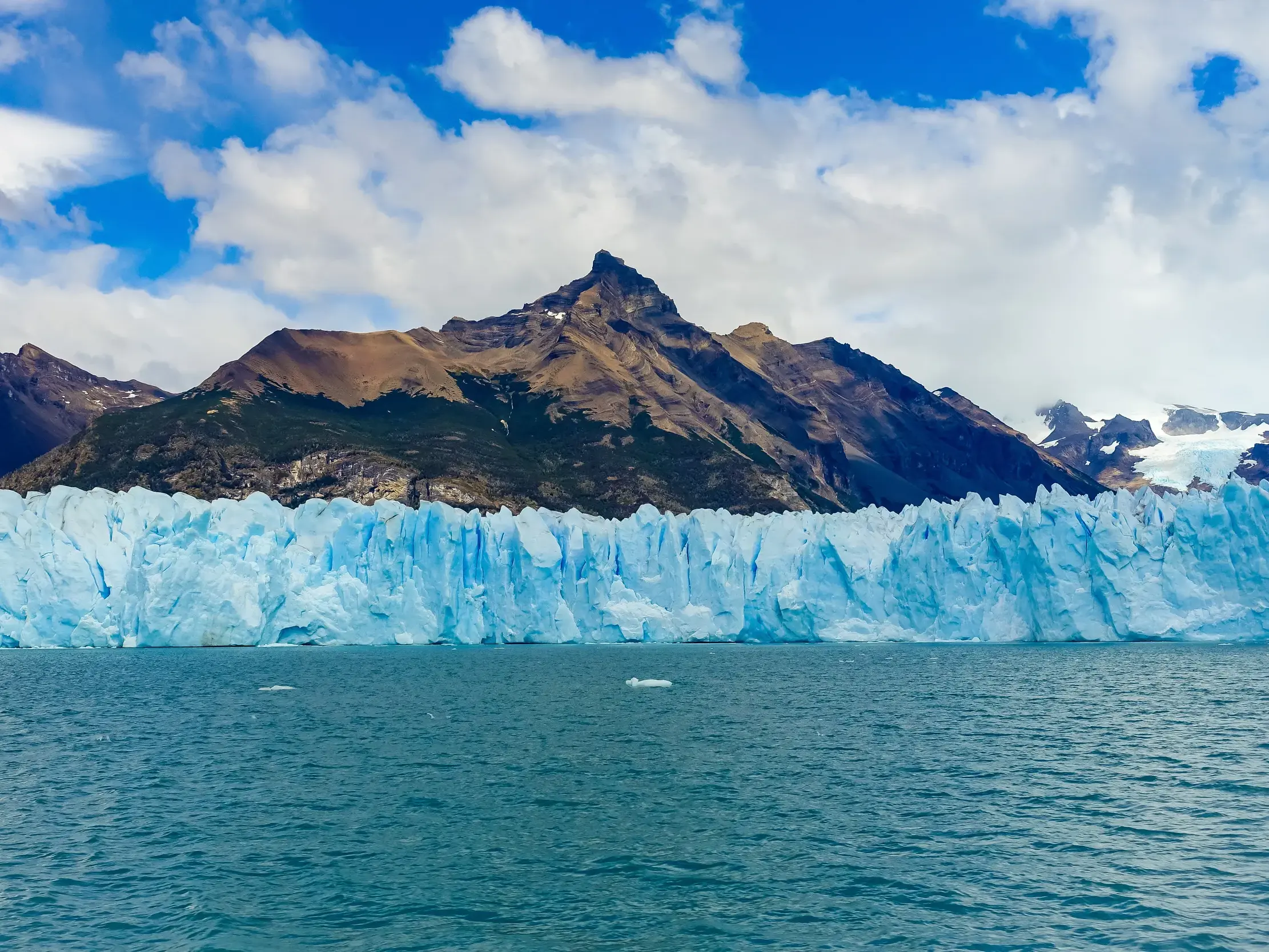 Blick vom Wasser auf die beeindruckende, hellblaue Eiswand des Perito Moreno Gletschers im Los Glaciares Nationalpark.