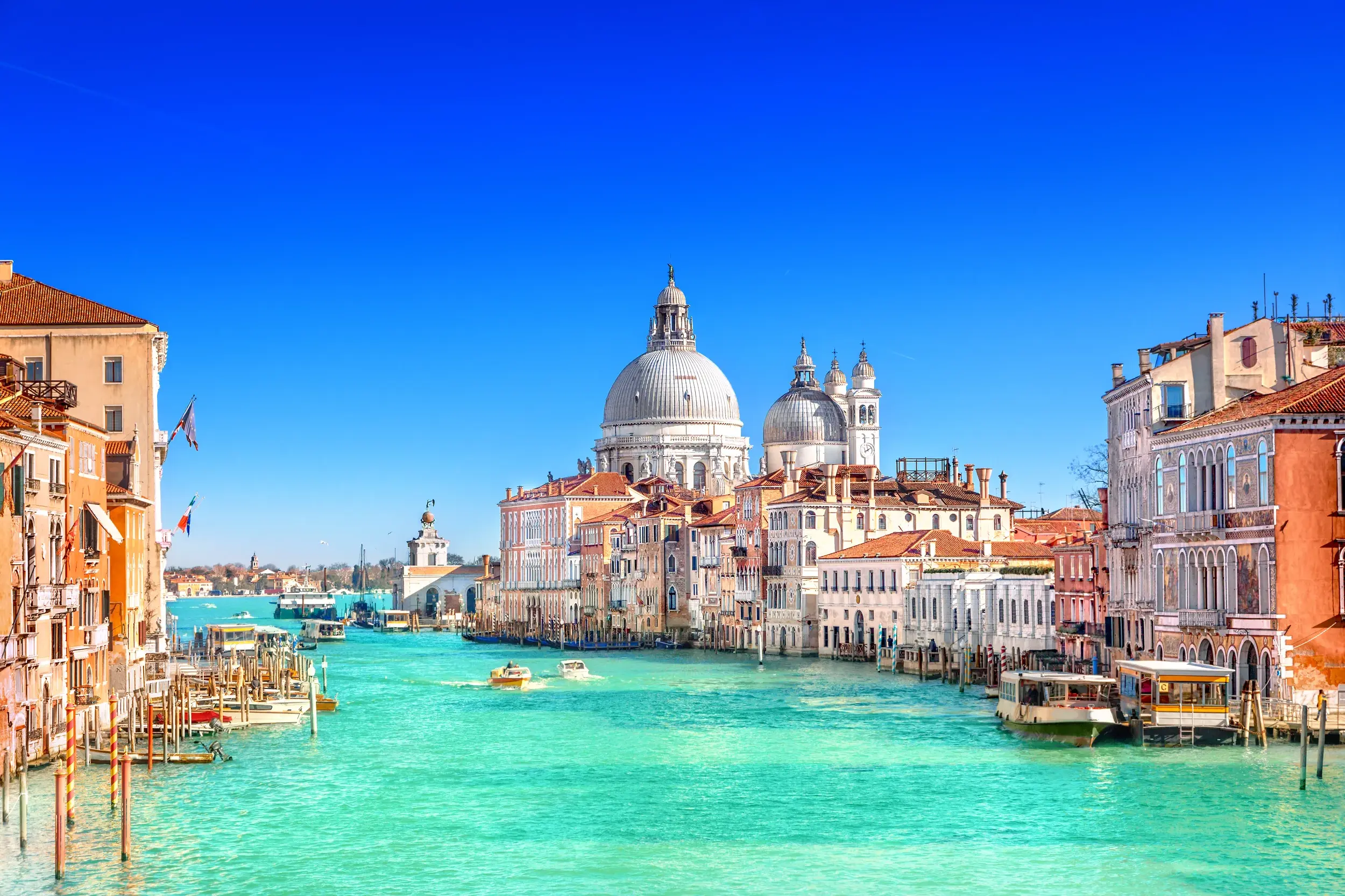 Blick über den türkisfarbenen Canal Grande in Venedig auf historische Paläste und die Basilika Santa Maria della Salute.