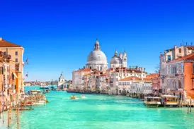 Blick über den türkisfarbenen Canal Grande in Venedig auf historische Paläste und die Basilika Santa Maria della Salute.