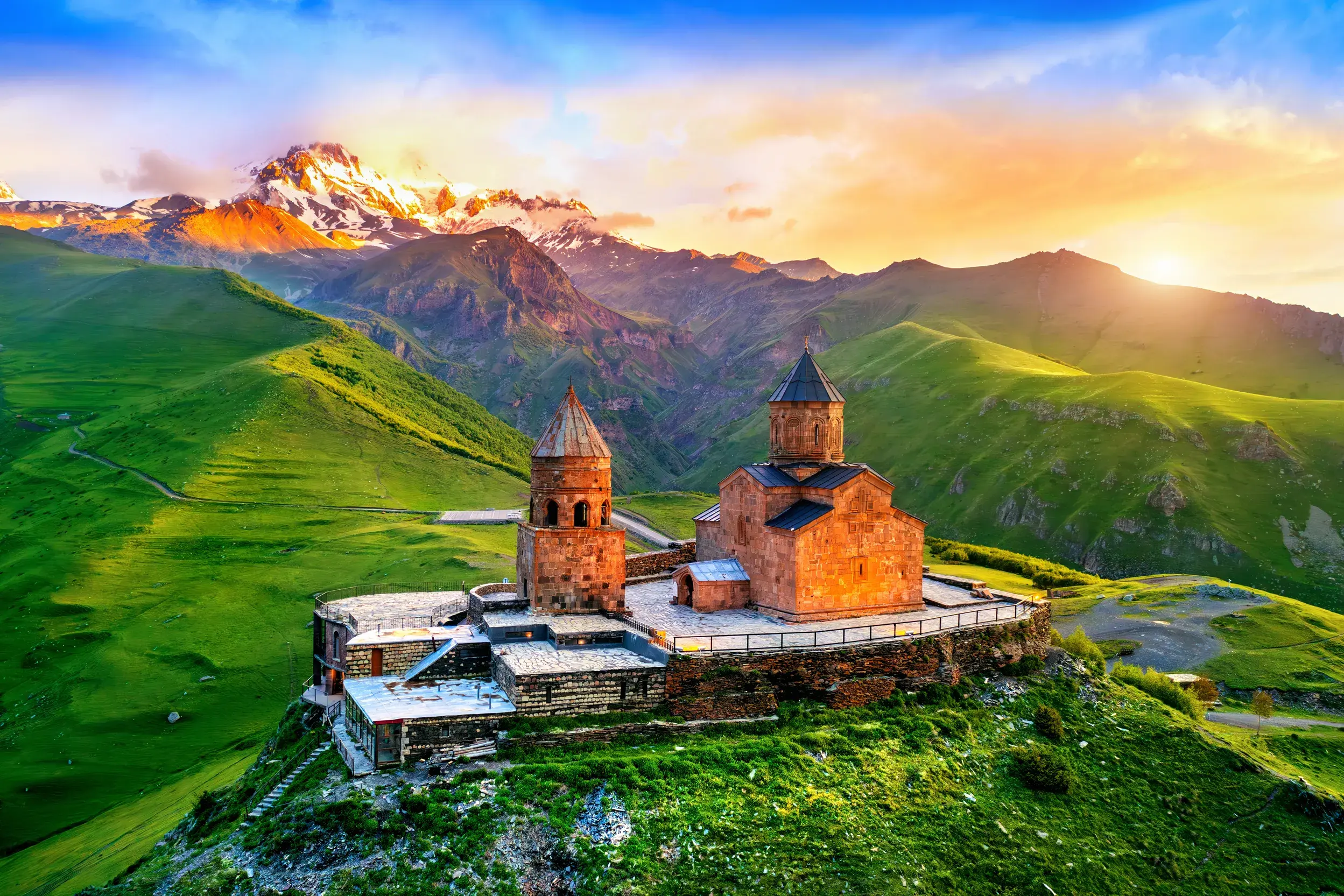 Gergeti-Dreifaltigkeitskirche in Georgien bei Sonnenaufgang, thronend auf einem Hügel vor dem schneebedeckten Kasbek-Gipfel.