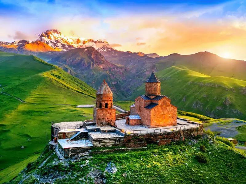 Gergeti-Dreifaltigkeitskirche in Georgien bei Sonnenaufgang, thronend auf einem Hügel vor dem schneebedeckten Kasbek-Gipfel.