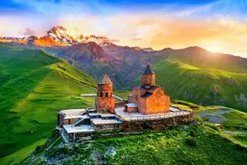 Gergeti-Dreifaltigkeitskirche in Georgien bei Sonnenaufgang, thronend auf einem Hügel vor dem schneebedeckten Kasbek-Gipfel.