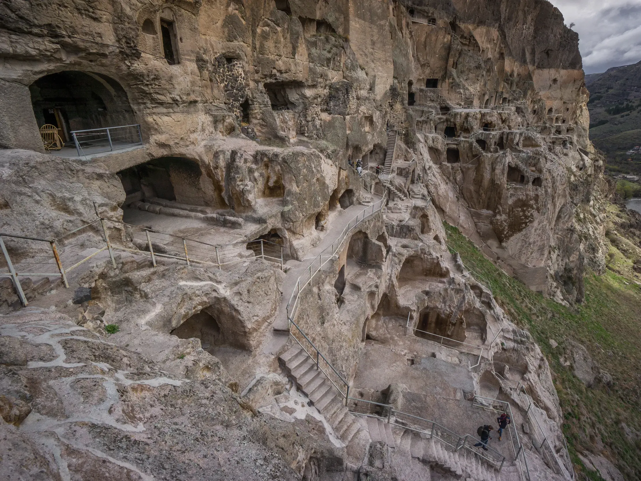 Wanderer erkunden die in Fels gehauenen Pfade und Höhlen der beeindruckenden Felsenstadt Wardsia in Georgien.