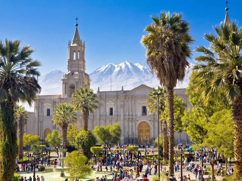 Sonniger Tag auf der belebten Plaza de Armas in Arequipa mit der Kathedrale vor der Kulisse des schneebedeckten Vulkans Misti.