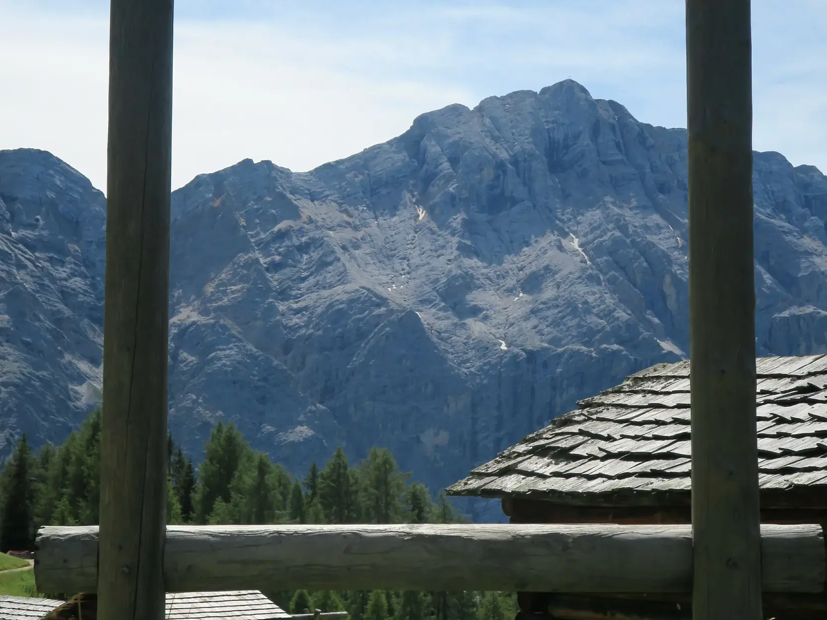 Ausblick von einem Holzbalkon auf die zerklüfteten Felswände des Pareskamms in den Dolomiten bei einer Wanderung in Südtirol.