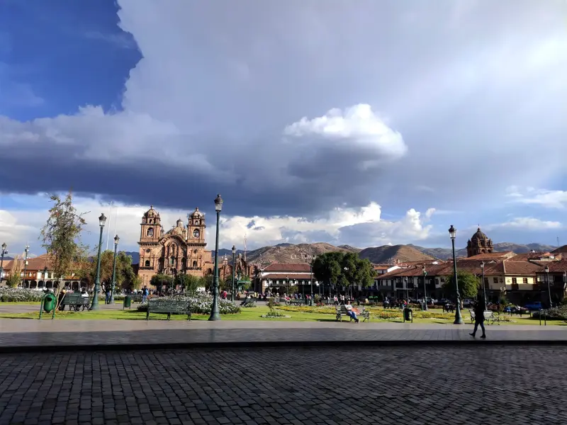 Der belebte Plaza de Armas in Cusco mit der Jesuitenkirche La Compañía de Jesús vor der Bergkulisse der Anden.
