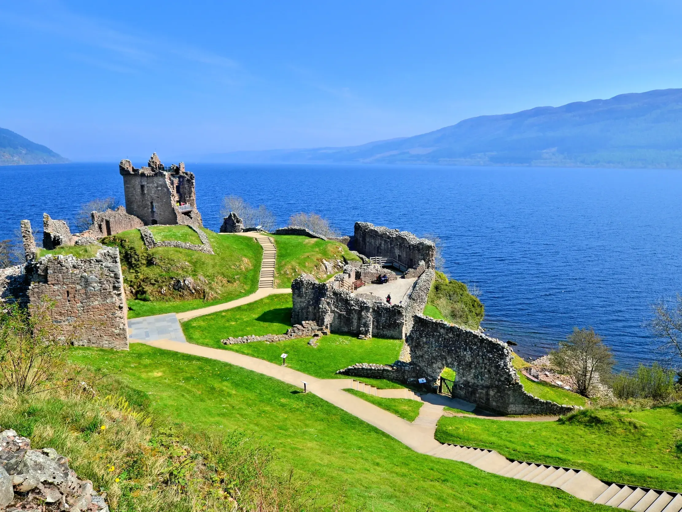 Malerische Ruine von Urquhart Castle am Ufer des tiefblauen Loch Ness in den schottischen Highlands.