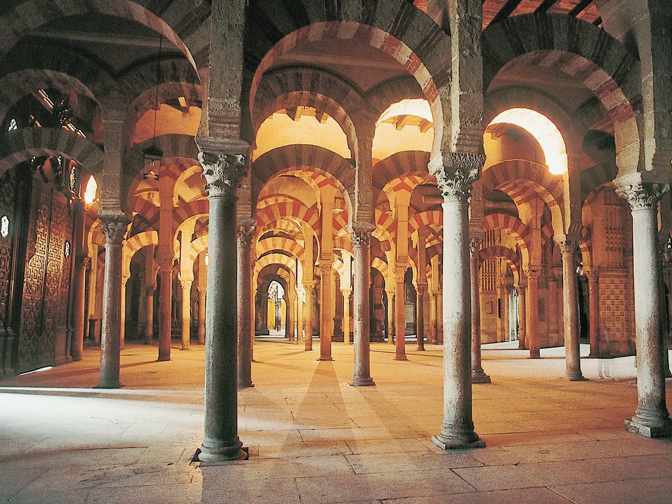 Ikonischer Säulenwald der Mezquita-Kathedrale in Córdoba mit charakteristischen rot-weißen, maurischen Hufeisenbögen.