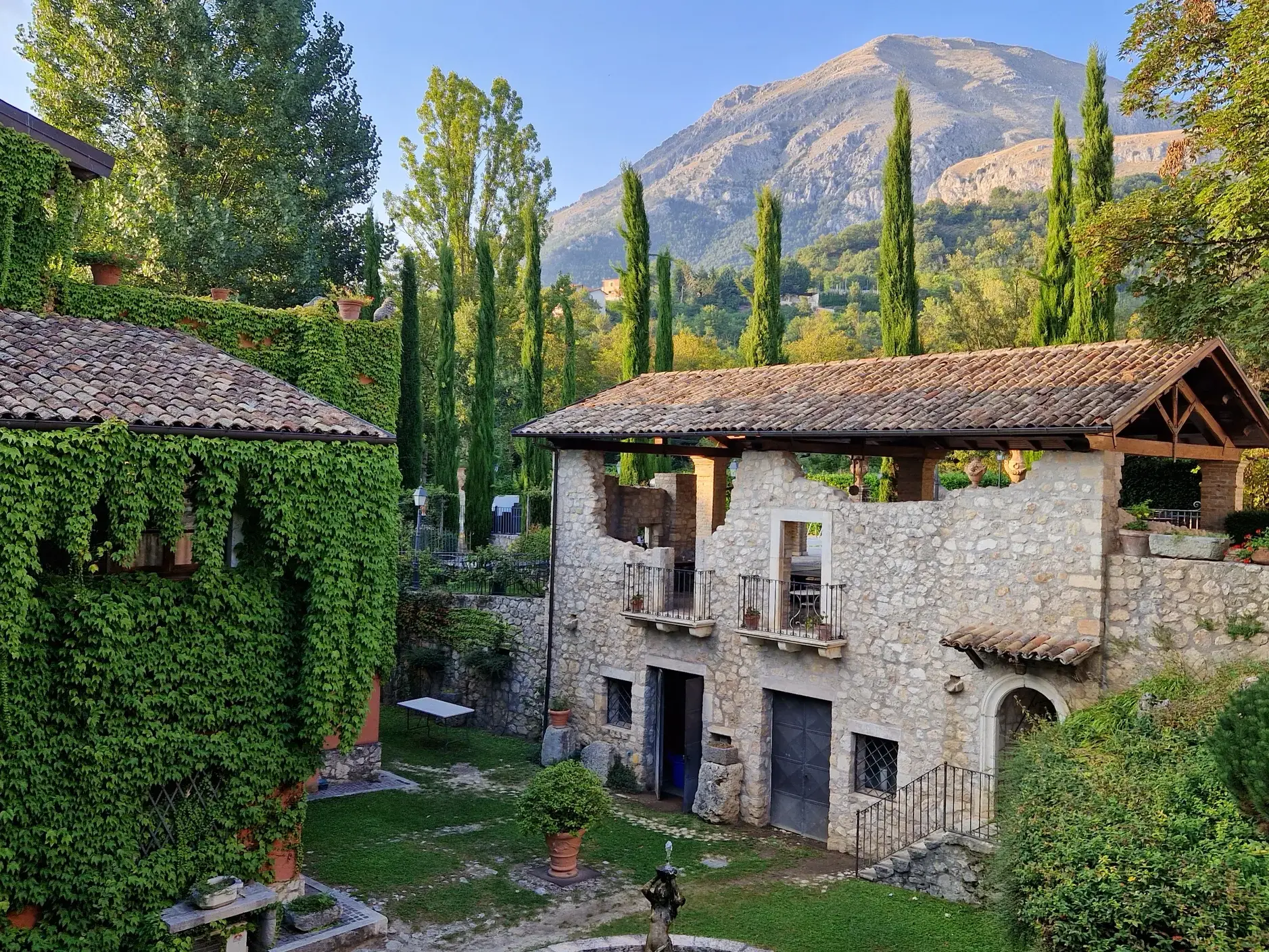 Efeubewachsenes Gästehaus und rustikales Steinhaus in den Abruzzen vor einer malerischen Bergkulisse bei einer Wanderreise.