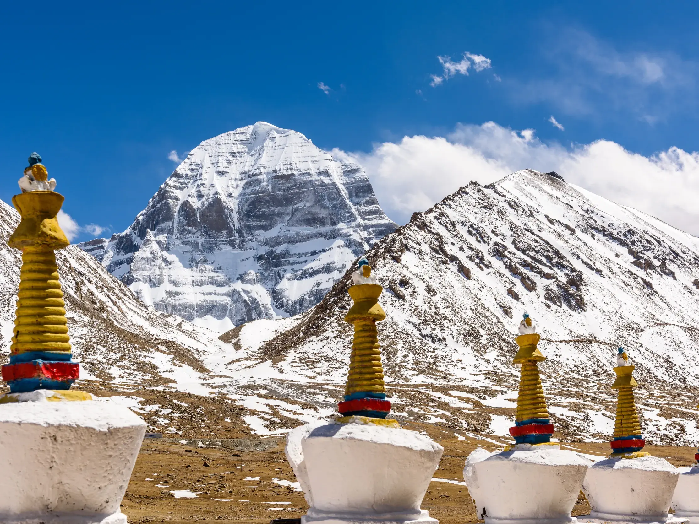 Majestätischer, schneebedeckter Gipfel des heiligen Berges Kailash in Tibet mit bunten Chörten im Vordergrund.