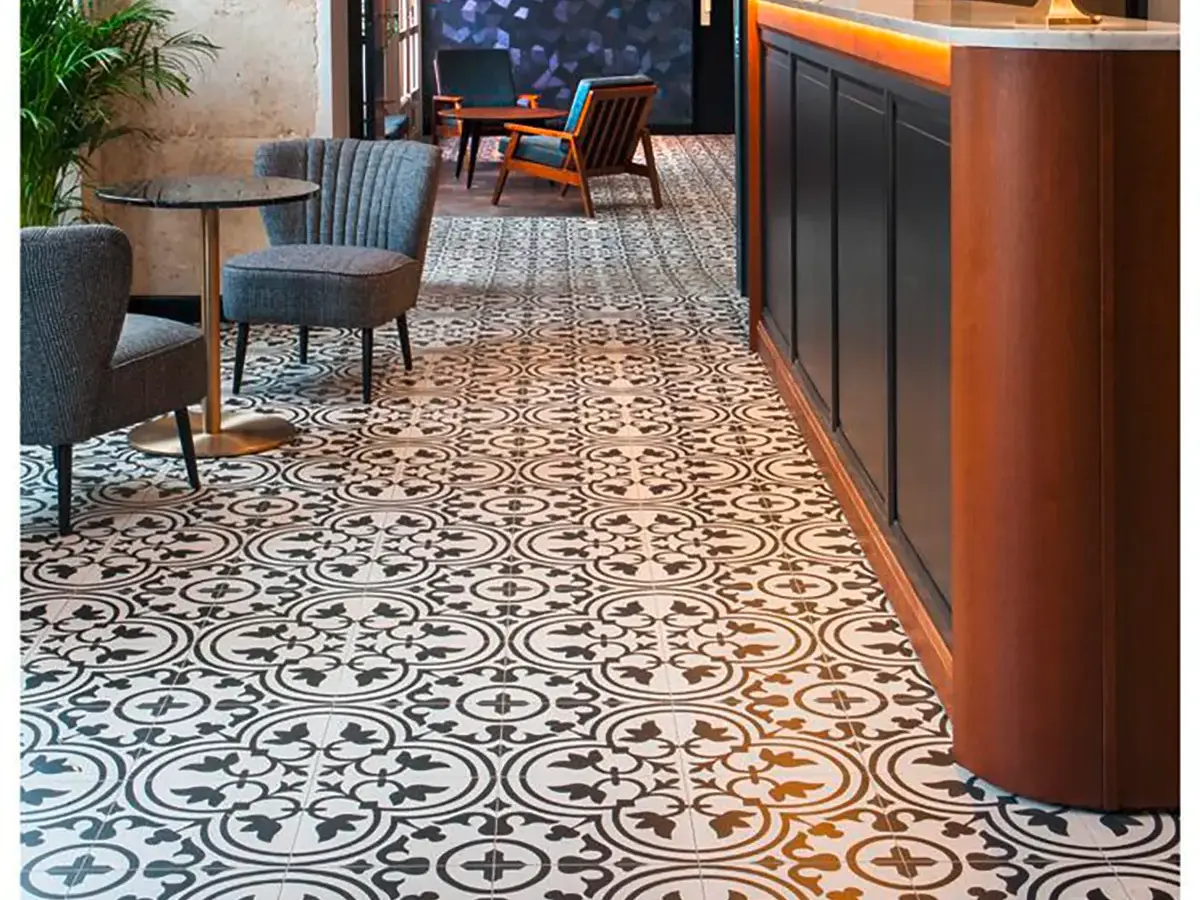Stilvoller Sitzbereich im Hotel André Latin in Paris mit modernen Sesseln auf einem schwarz-weiß gemusterten Fliesenboden.