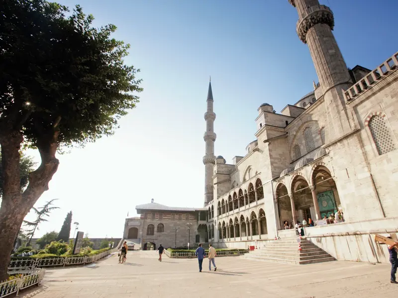 Die sonnige Fassade der Blauen Moschee in Istanbul mit Minaretten und Touristen auf dem Vorplatz am Sultanahmet-Platz.