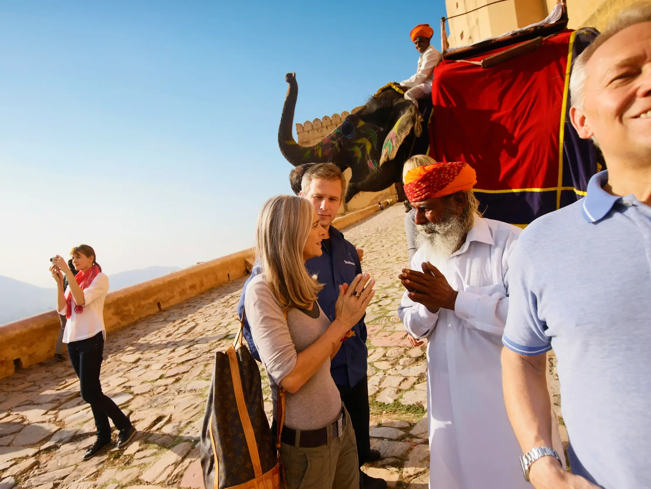 Ein Mann mit Turban begrüßt eine Teilnehmerin einer Studiosus-Studienreise herzlich mit Namaste-Geste am Amber Fort in Jaipur.