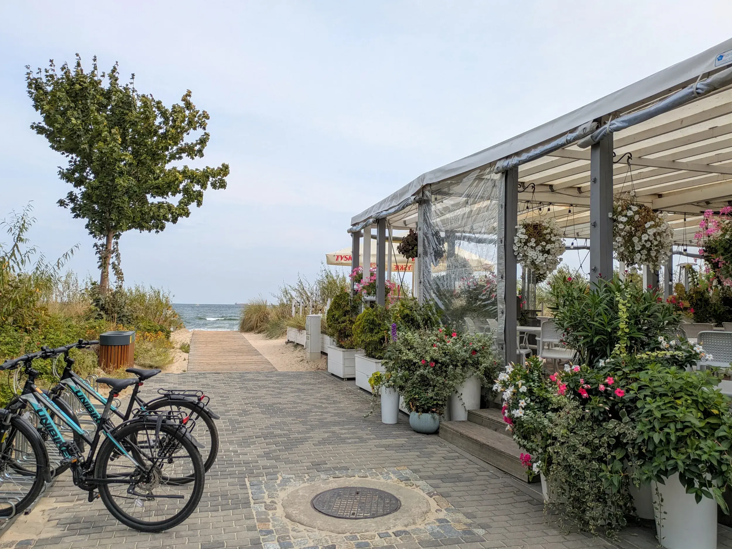 Einladendes Restaurant an der Strandpromenade von Misdroy mit geparkten Fahrrädern und Weg zum Sandstrand der Ostsee.