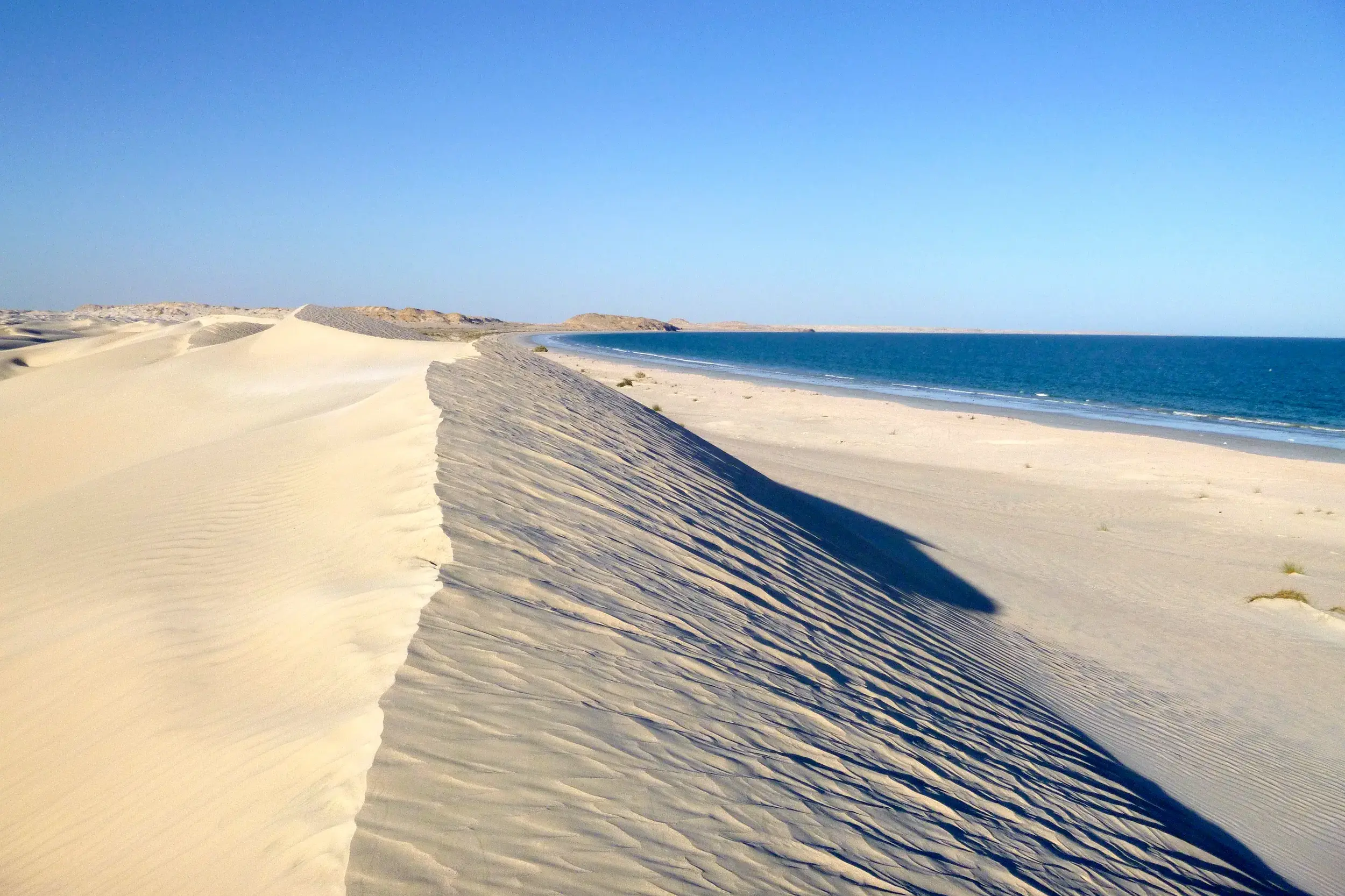 Wanderung durch die weißen Sugar Dunes von Al-Khaluf, die bei strahlendem Sonnenschein an den blauen Ozean im Oman grenzen.