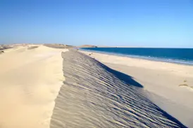 Wanderung durch die weißen Sugar Dunes von Al-Khaluf, die bei strahlendem Sonnenschein an den blauen Ozean im Oman grenzen.