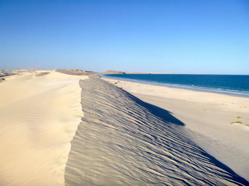 Wanderung durch die weißen Sugar Dunes von Al-Khaluf, die bei strahlendem Sonnenschein an den blauen Ozean im Oman grenzen.