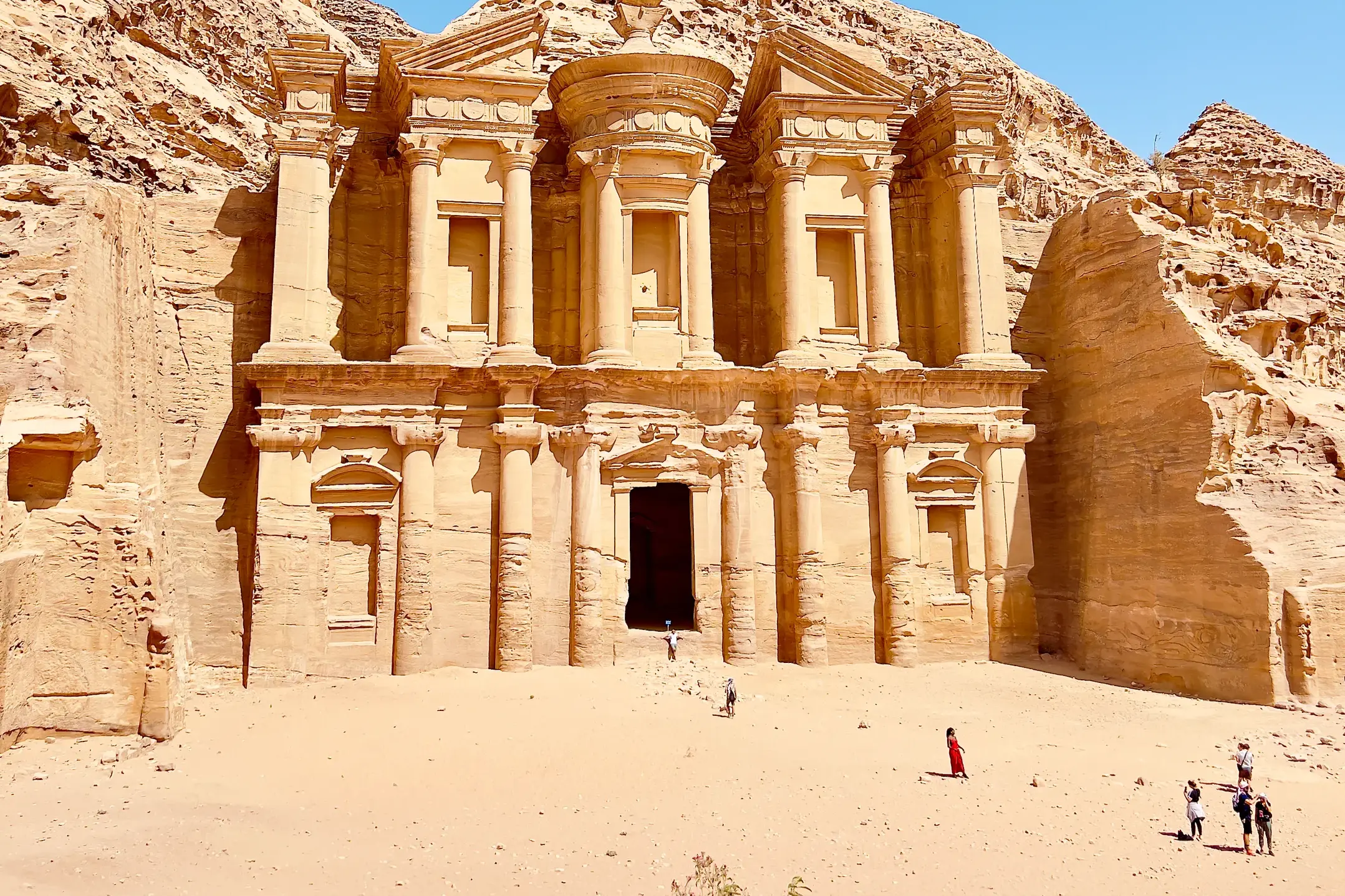 Imposante Fassade des in den Fels gehauenen Klosters Ad-Deir in Petra, Jordanien, mit Besuchern davor.