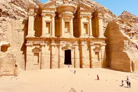 Imposante Fassade des in den Fels gehauenen Klosters Ad-Deir in Petra, Jordanien, mit Besuchern davor.