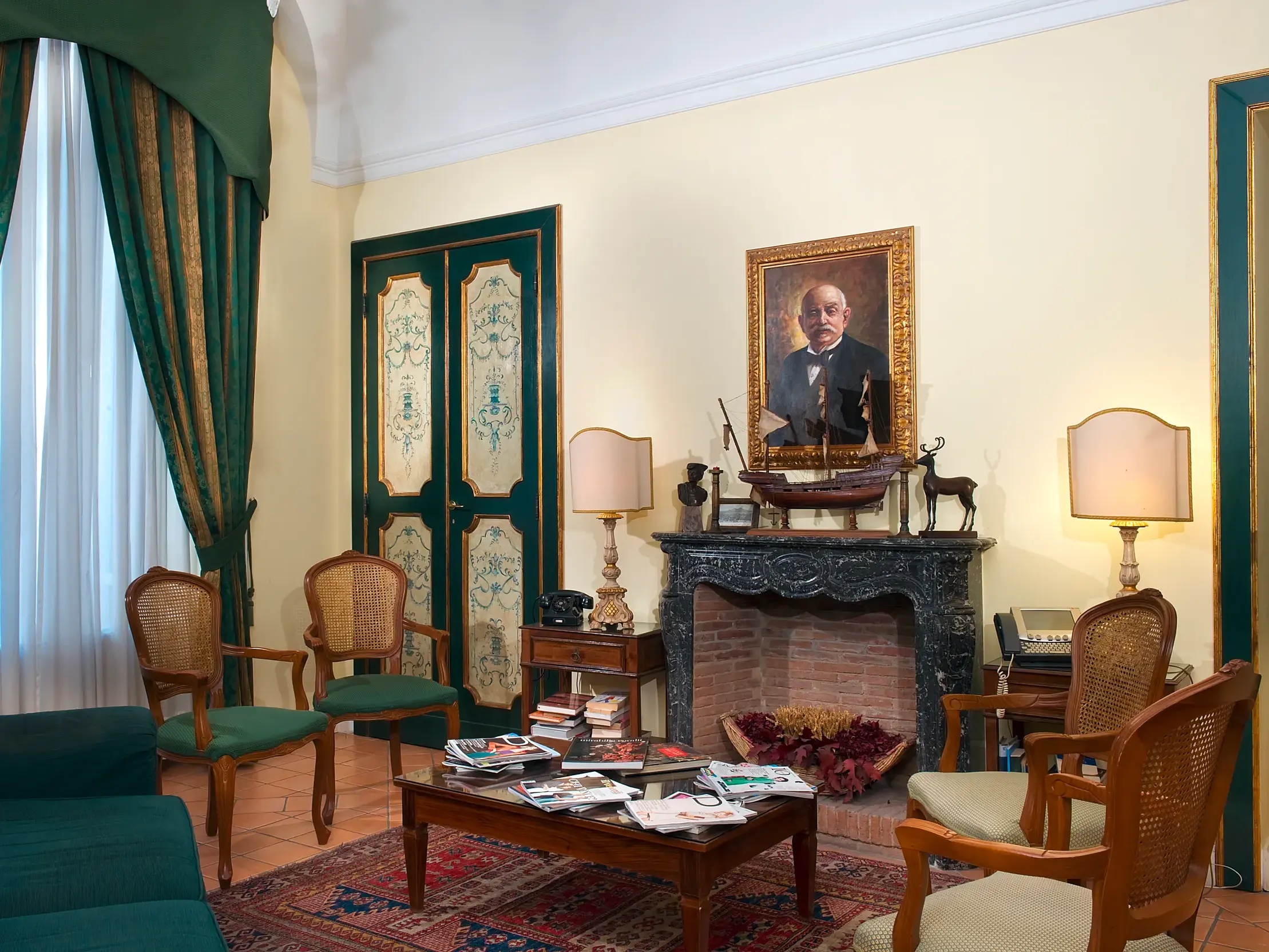 Stilvoller Salon mit Kamin und historischen Möbeln im Hotel Chiaja, einem Patrizierhaus aus dem 18. Jahrhundert in Neapel.