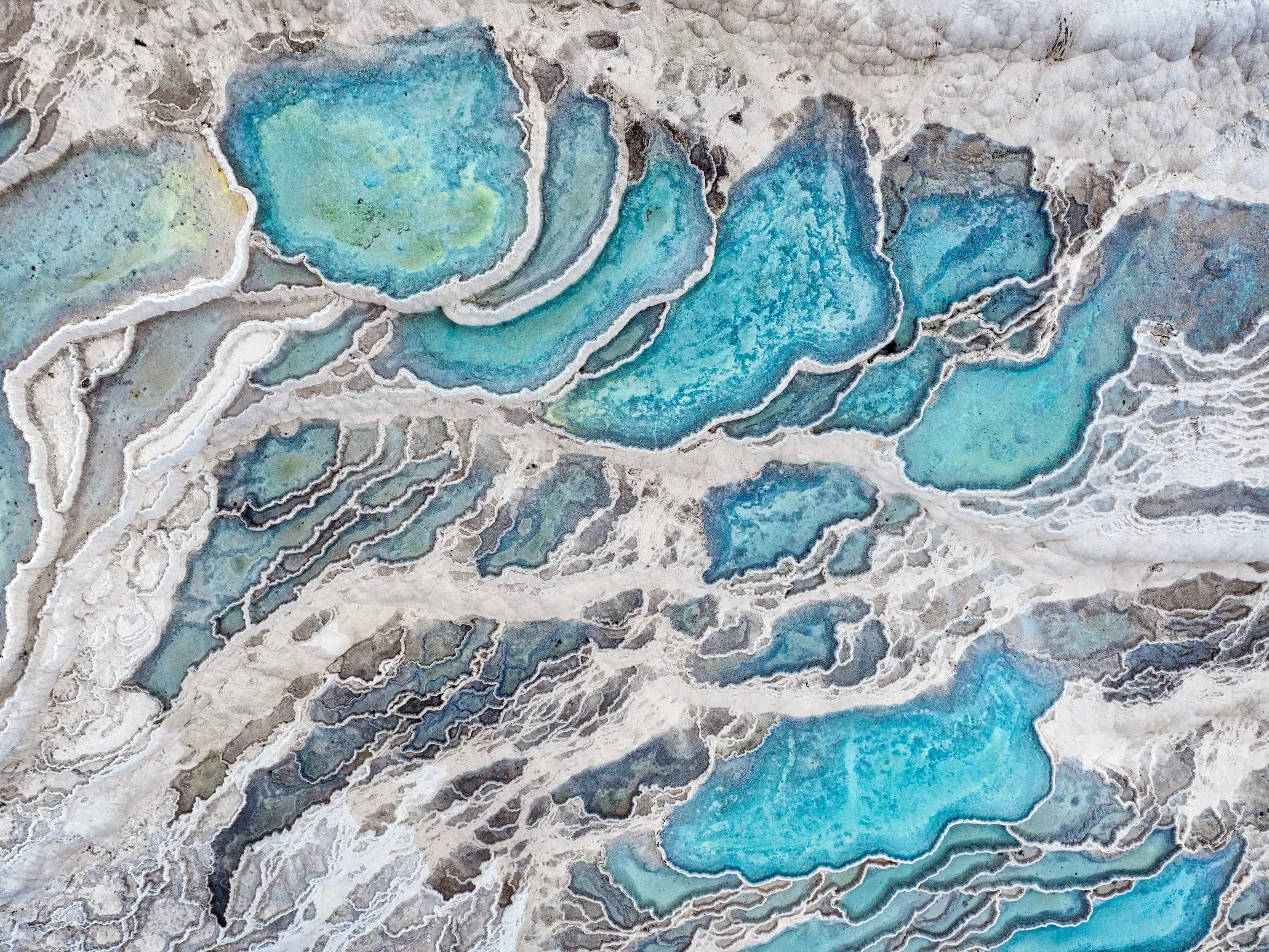 Luftaufnahme der weißen Kalksinterterrassen von Pamukkale, einem UNESCO-Welterbe, mit türkisfarbenem Thermalwasser.