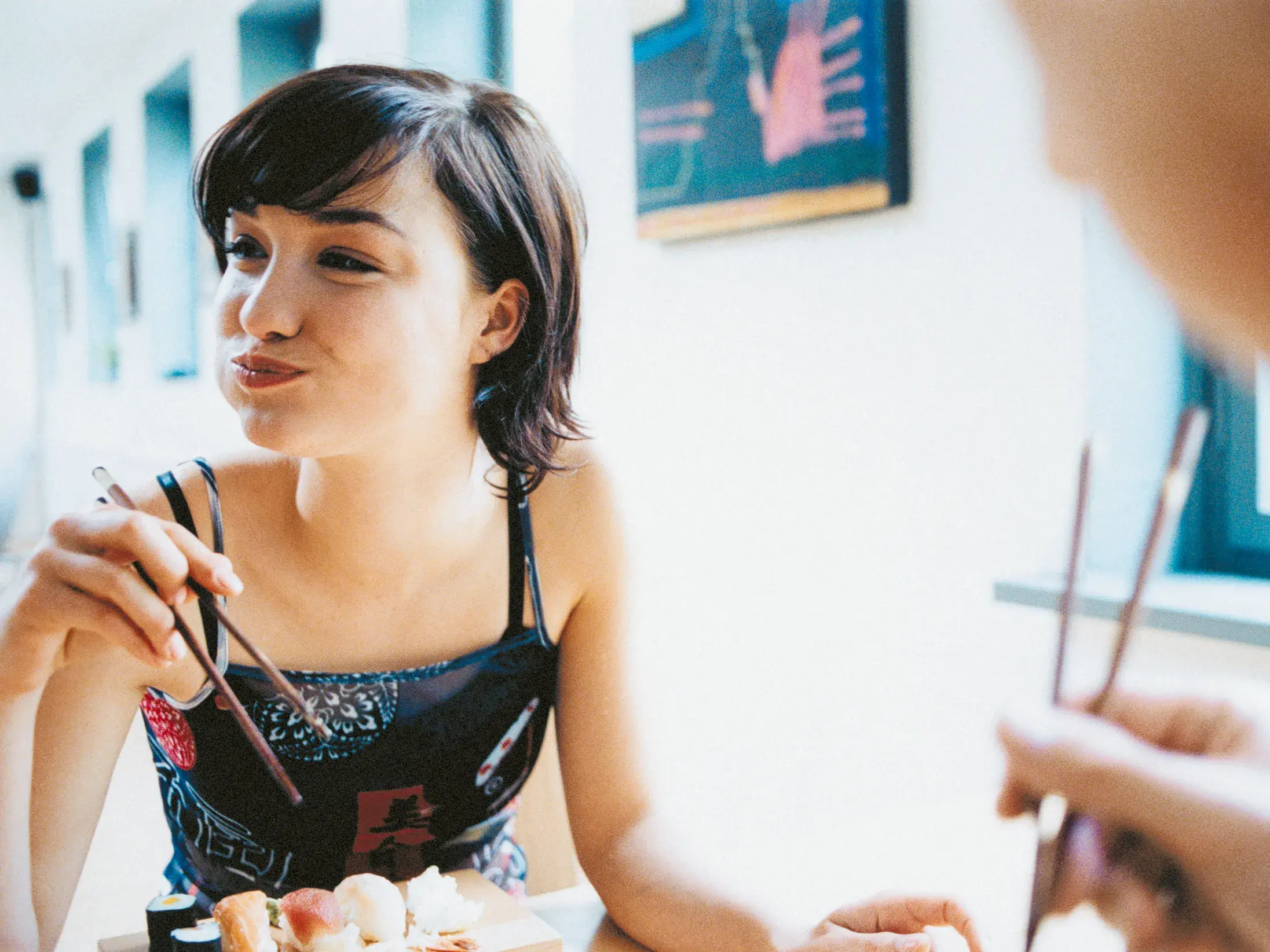 Eine junge Frau genießt sichtlich eine Auswahl an Sushi mit Stäbchen in einem Restaurant während einer Japan-Studienreise.