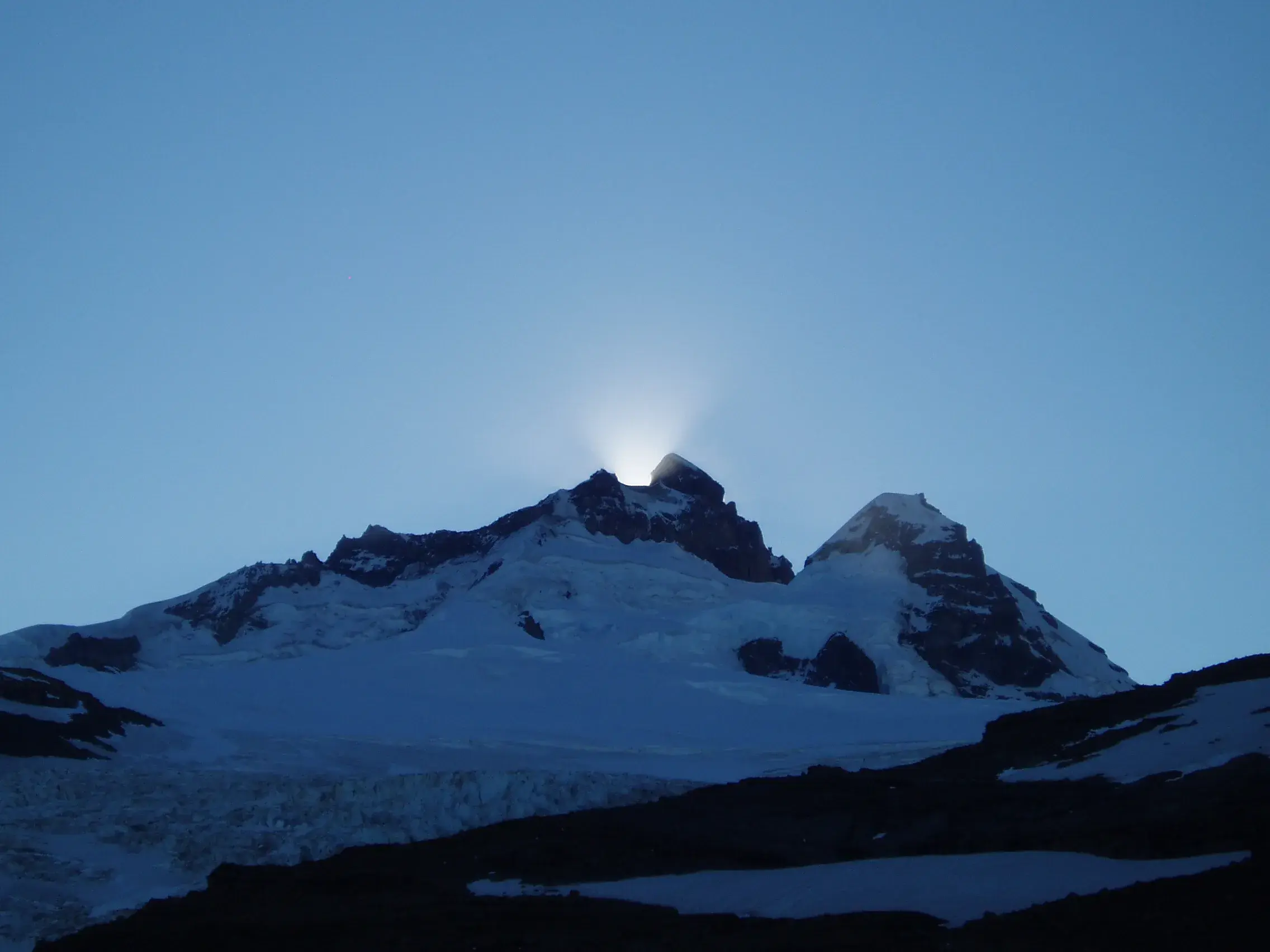 Die aufgehende Sonne strahlt hinter dem schneebedeckten Mount Tronador hervor
