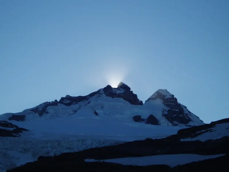 Die aufgehende Sonne strahlt hinter dem schneebedeckten Mount Tronador hervor